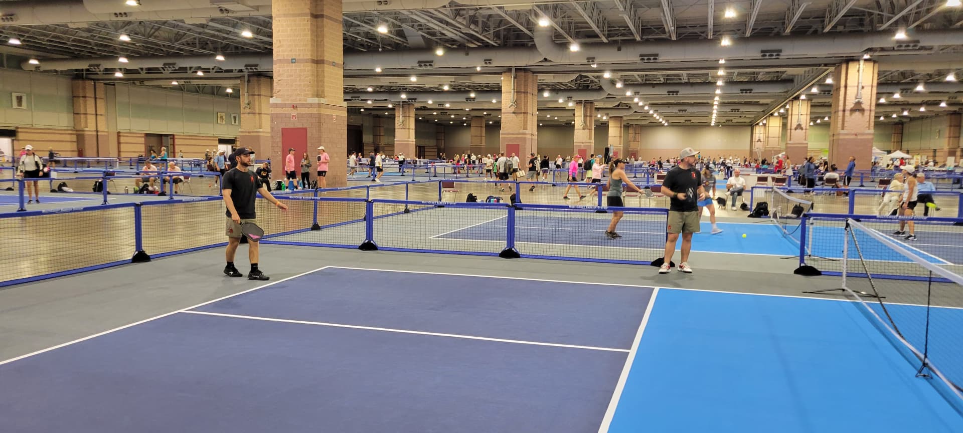 Convention center filled with rollout pickleball courts during a tournament