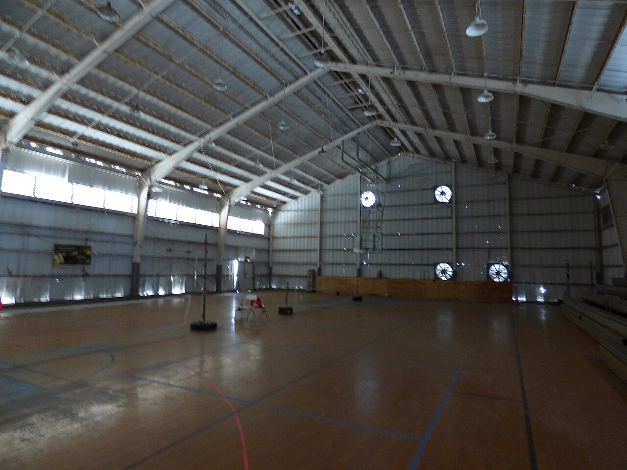A gym floor set up with portable pickleball nets and no divider between courts